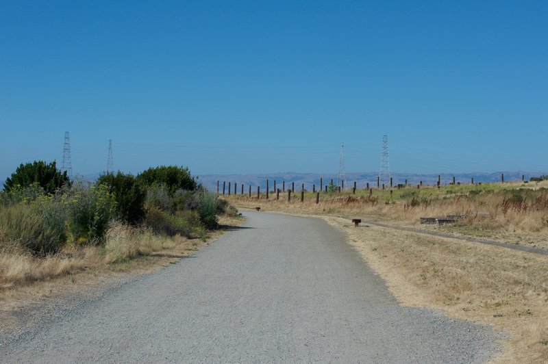 The trail departs the parking lot via a wide, gravel trail that leads out to the South San Francisco Bay.