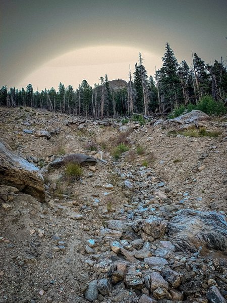 9880' elevation, looking east and upwards at the massive landslide field. Early morning 08:30 aura of the sun rising east, not a rainbow, just light flare on a clear day. See the topographical map for a sense of the landslide's scale.