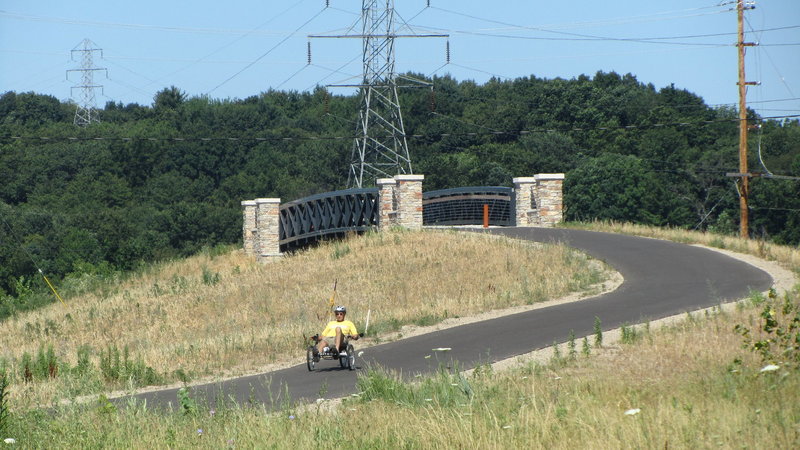 Recumbent Trike At Bridge Over Maynard" by John Eisenschenk (https://tinyurl.com/u4emtb8), Flickr licensed under CC BY 2.0 (https://creativecommons.org/licenses/by/2.0/).