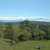 The Santa Cruz Mountain are southwest in the far distance, with Loma Prieta, 3,790 ft., their highest peak, on the left, as Yerba Buena Trail winds through the spring green hills of the Diablo Range.