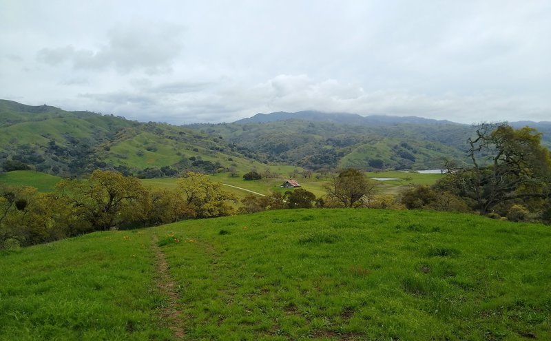 The spring green Diablo Range in the distance, with the historic Washburn Barn and Grant Lake in the valley below, are seen from Edwards Loop Trail.