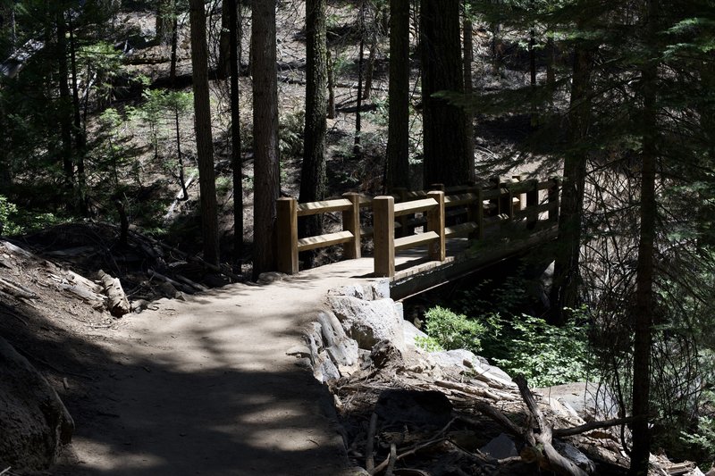 A bridge crosses a small creek as it makes its way up to the Mariposa Grove parking area.