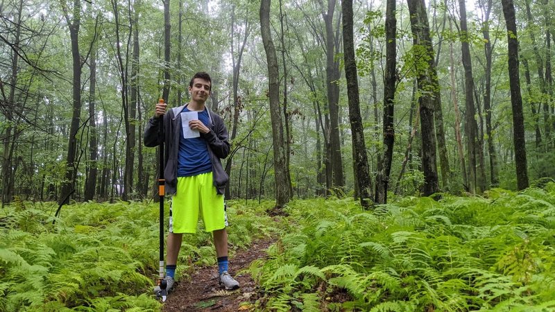 Volunteer taking trail measurements and mitigating poison ivy