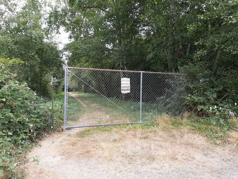 A closed gate with foot path access at the side.