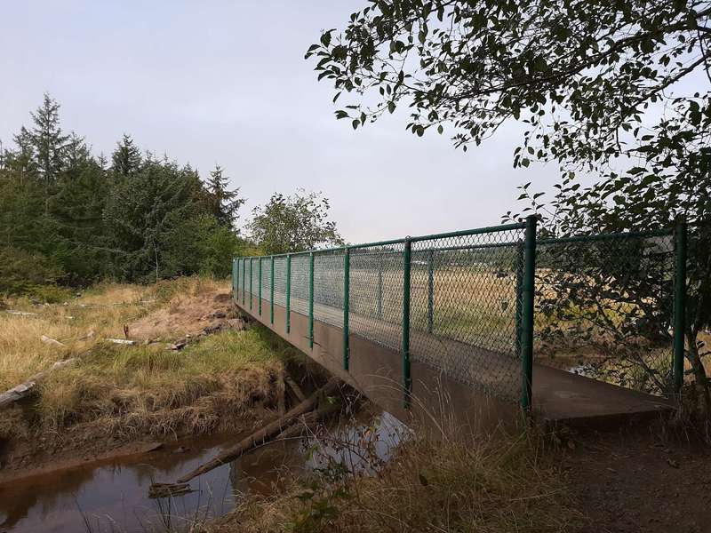A bridge over a creek with fenced railings.