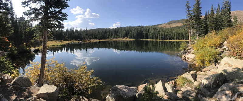 Clouds reflect on a perfectly still inky lake.