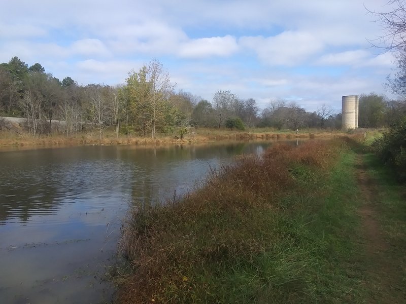 Fall view of pond with train tracks and silo in background.