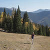Hiker crossing an alpine meadow framed by the Taos Ski Area mountains