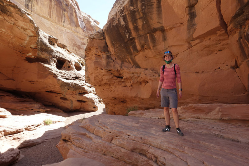 Hiker posing on a shaded slickrock ledge in Bell's Canyon.