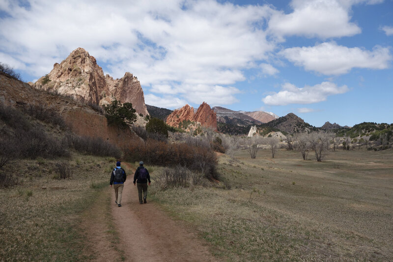Two hikers on the Ute trail walking in the direction of Gray Rock (left) and the Gateway Rocks (center) at Garden of the Gods.