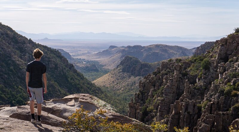 A hiker looking out from the edge of the Chiricahua Mountains.