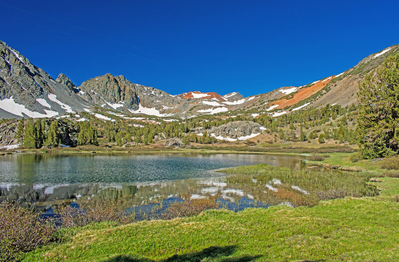 The first of the 3 Frog Lakes. Some of the mineral rich soils appear brilliant orange in direct morning or evening sunlight. Burro Pass in the low point in the ridge in front of the orange mountain.