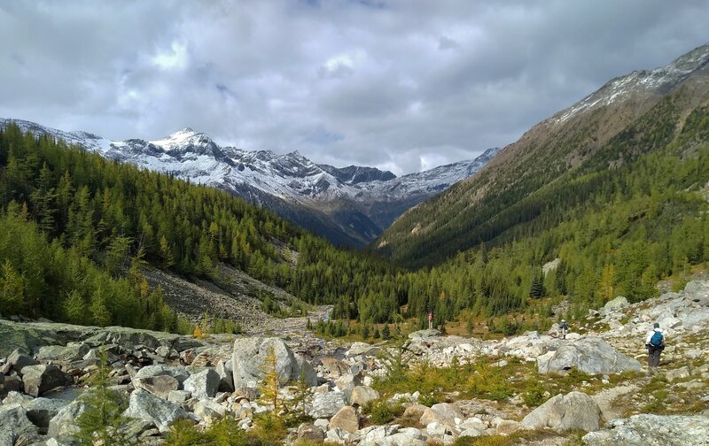 Snowy mountains in the distance on the other side of Horsethief Creek valley are seen hiking north along the outlet creek of Lake of the Hanging Glacier.