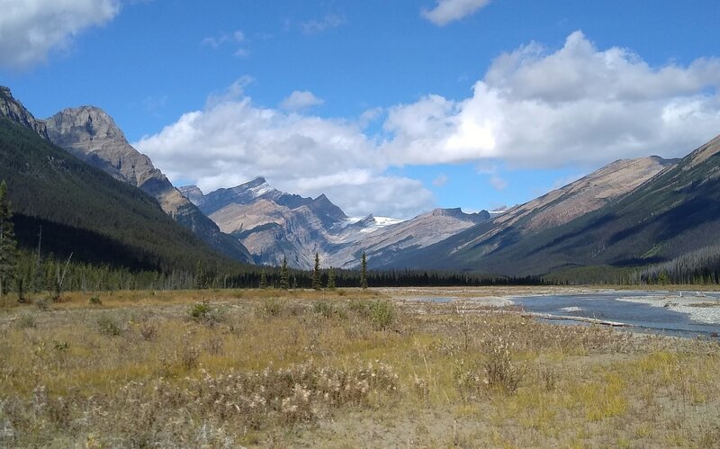 In the distance, Lynx Mountain is the pointy mountain on the left. Reef Glacier flows down from Reef Icefield in the far distance (center). Seen from the gravel flats of Resplendent Creek, looking northwest near Resplendent trail camp.