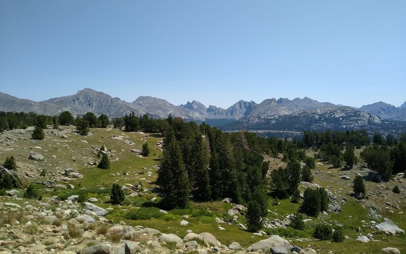 The high rocky, grass meadows of the Wind Rivers. The three peaks in the center in the far distance are the back/west side of Cirque of the Towers.