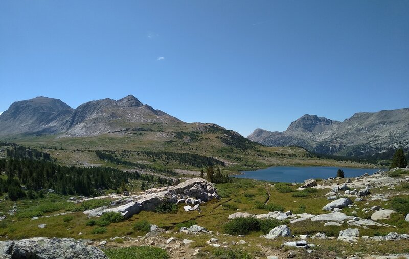 Pretty, jewel-like Lake 10322 sparkles in the high meadows along Hay Pass Trail. Mt. Victor, 12,254 ft., is the double humped massif on the left. On the right North Fork Peak, 11,175 ft., is the prominent Peak.