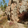 The trail turns to pavement as it runs along the rock outcrops and a cave entrance.