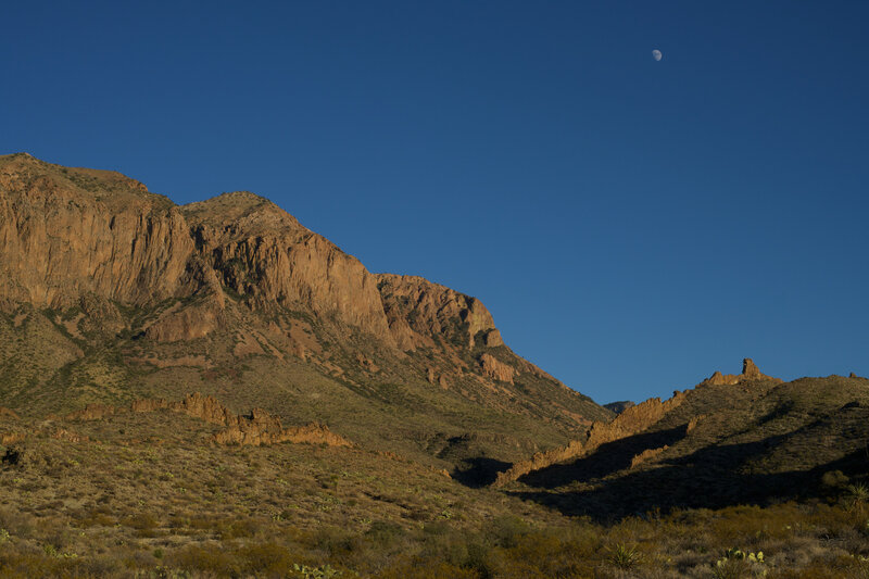 The Chisos Mountains, rock walls and moon from the Ward Spring Trail at sunset.