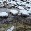 Snow covered rocks in icy creek.
