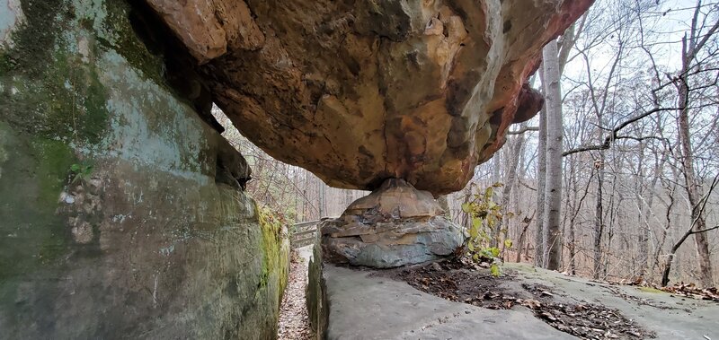 A large boulder suspended over the trail and supported by smaller rock.