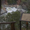 A wooden bench and interpretive sign appear at the first view of Indian Creek Falls.