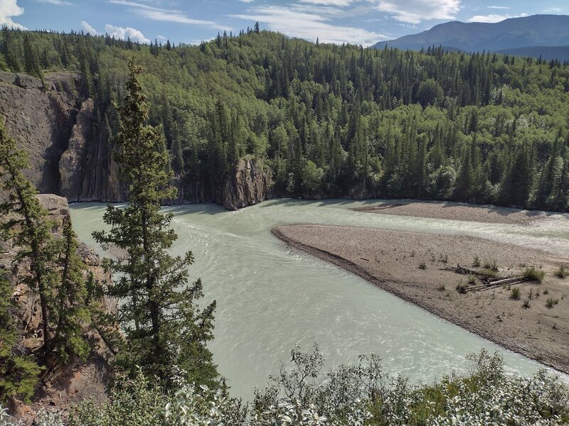 The silty Smoky River flowing right to left, entering the Sulphur Gates cliffs on the left to meet the Sulphur River (not seen) out of view to the left.