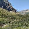 Siyeh Creek (lower left) runs in the valley below.  Massive cliffs (left) of the east face of Piegan Mountain, 9,219 ft., rise above the creek.