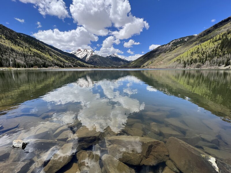 Reflection of snow capped peaks and fluffy clouds in Crystal Lake