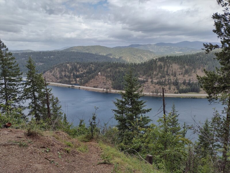 Wolf Lodge Bay, an eastern arm of Lake Coeur d'Alene, is seen below from the north side of Mineral Ridge.  Forested hills and mountains stretch into the distance.