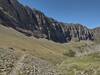 Looking up at massive walls capped by the Great Divide with the trail running up close at the foot of them.