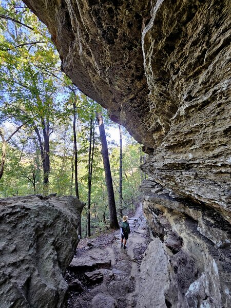 The trail squeezes beneath an overhanging cliff.