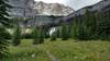 Crossing a grassy meadow when approaching Petain Falls in its amphitheater of waterfalls.